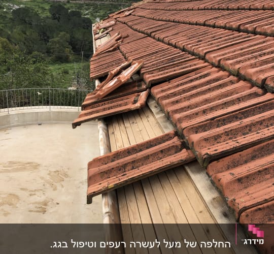 רעפים שבורים על גג עץ עם רעפים אדומים